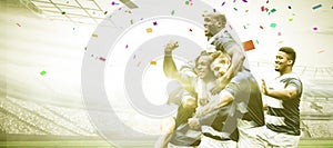 Digital composite image of team of rugby players celebrating a win in sports stadium
