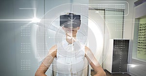 Digital composite image of tech graphics with businesswoman using VR glasses in office