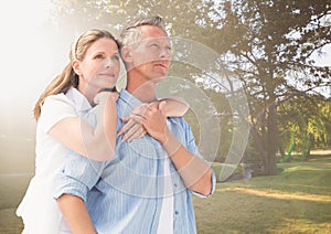 Middle aged couple embracing in blurry park with flare