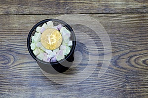 Digital currency physical gold bitcoin coin in jar with marshmallows.