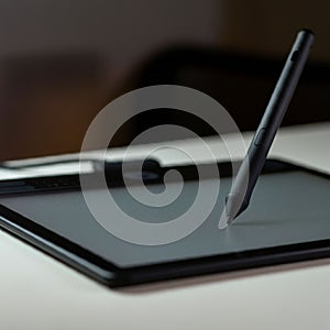 A digital drawing tablet with a stylus poised on its surface. The tablet features a