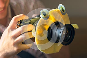 The digital DSLR camera in a hand with a children`s toy on the camera lens to attract the child`s attention. Male hands with