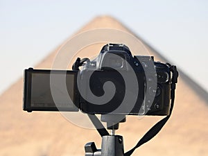 A digital DSLR camera on a tripod Photographing The red north pyramid of Dahshur of king Sneferu, named for the rusty reddish hue