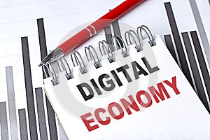 DIGITAL ECONOMY text written on notebook with pen on chart