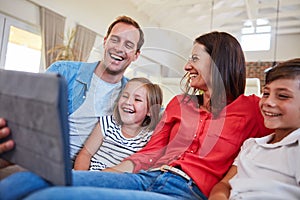 Digital entertainment for the whole family. smiling parents sitting with their young son and daughter on their living