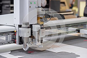 Digital flatbed cutter, plotter cutting white cardboard sheet at exhibition