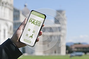 Digital Green Pass concept: Woman hold a smartphone in front of the Pisa leaning tower that show an hypotetical app for the