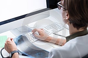 Digital health concept: young medical doctor working at a desktop computer. Female practitioner at modern medical doctor office e