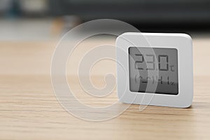 Digital hygrometer with thermometer on wooden table indoors. Space for text