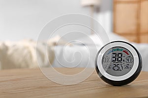 Digital hygrometer with thermometer on wooden table indoors. Space for text