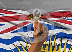 Digital ID British Columbia on finger of dark skin person and Canadian province flag on background