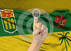 Digital ID Saskatchewan on finger of white skin person and Canadian province flag on background