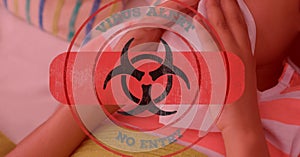 Digital illustration of a hazard sign with a bandage and Virus alert over a boy wiping his nose