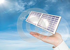 Digital image of solar panel on hand against sky