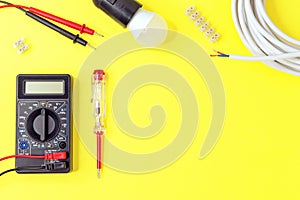Digital multimeter and indicator screwdriver on a yellow background. Voltmeter, ohmmeter, ammeter
