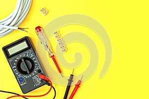 Digital multimeter and indicator screwdriver on a yellow background. Voltmeter, ohmmeter, ammeter