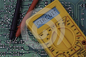 Digital multimeter multitester on a circuit board with the word circuit