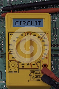 Digital multimeter multitester on a circuit board with the word circuit