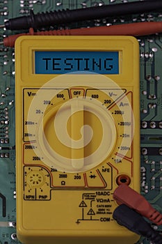 Digital multimeter multitester on a circuit board with the word testing