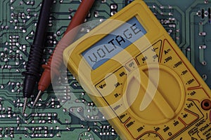 Digital multimeter multitester on a circuit board with the word voltage