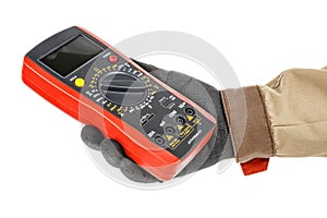 Digital multimeter with red rubber protective case in electrician hand in black protective glove and brown uniform isolated on