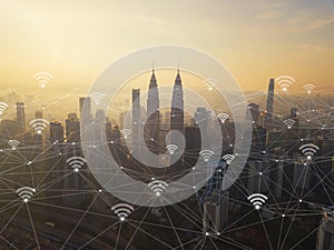 Digital network connection lines and wifi icons with Kuala Lumpur Downtown, Malaysia. Financial district in smart city in