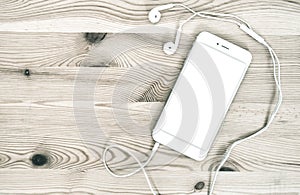Digital phone headphones on wooden background