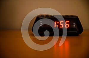 Digital radio alarm clock sitting on a table in a bedroom at night