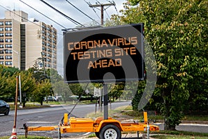 Digital road sign by a suburban street that says Coronavirus Testing Site Ahead.