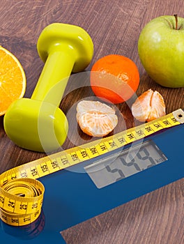 Digital scale with tape measure, dumbbells and fruits. Slimming concept