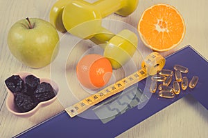 Digital scale with tape measure, dumbbells, tablets and fruits. Healthy lifestyles and slimming concept