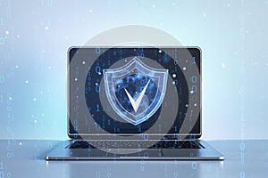 Digital shield icon on laptop screen with binary code floating around