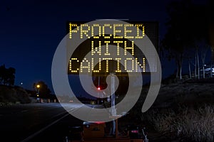 Digital sign at a freeway onramp stating Proceed With Caution