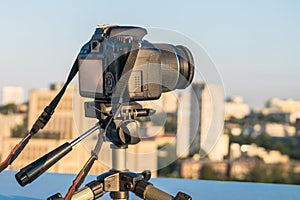 A digital SLR camera is mounted on a tripod. The shooting of the cityscape from the roof