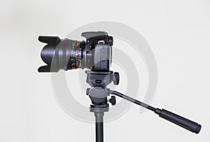 Digital SLR camera on a tripod with a removable manual lens on a gray background. Shooting in the interior