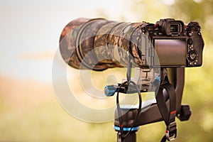 Digital slr or mirrorless camera with camouflage cover for shooting of nature