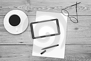 Digital tablet, blank papers, coffee cup, eyeglasses and pen on wooden background. Copy space.