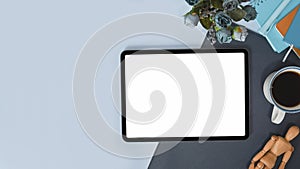 Tablet with with blank screen, coffee cup and notebook on stylish workspace.