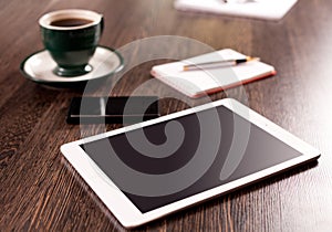 Digital tablet computer with note paper and cup of coffee on old wooden desk