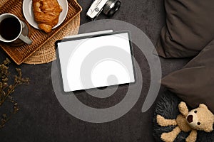 Digital tablet with empty screen, teddybear and camera on gray carpet.