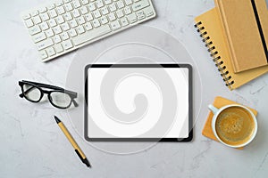 Digital tablet mock up, coffee cup, notebooks and computer keyboard on modern office desk. Top view, flat lay