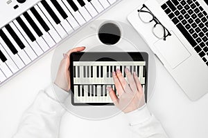 Digital tablet with piano, laptop and synthesizer on a white background.