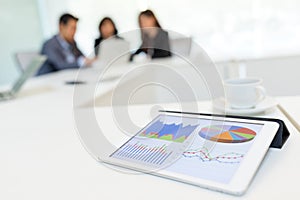 Digital tablet showing graph with business partners discussing i