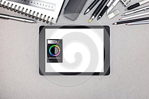 digital tablet, spiral notebook and various drawing tools on gray paper background