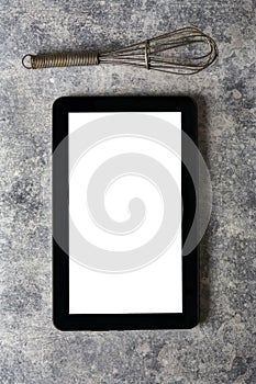 Digital tablet, with whisk and antique silverware, on grunge bac