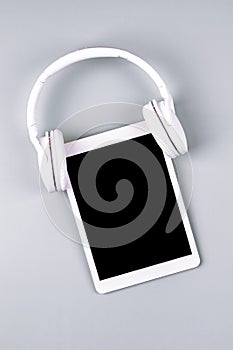 Digital tablet with wireless headphones on gray background. Online learning, remote education, e-learning, technology