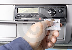 Digital tachograph and drivers hand inserting the digital card in the slot for the second driver