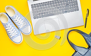 Digital technology and fashionable women's accessories on a yellow background: laptop, usb flash drive, bag, wallet, sneakers