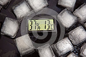 the digital thermometer for measuring air temperature and humidity against the background of frozen ice