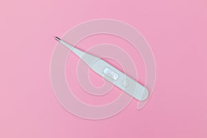 A digital thermometer on a pink background.